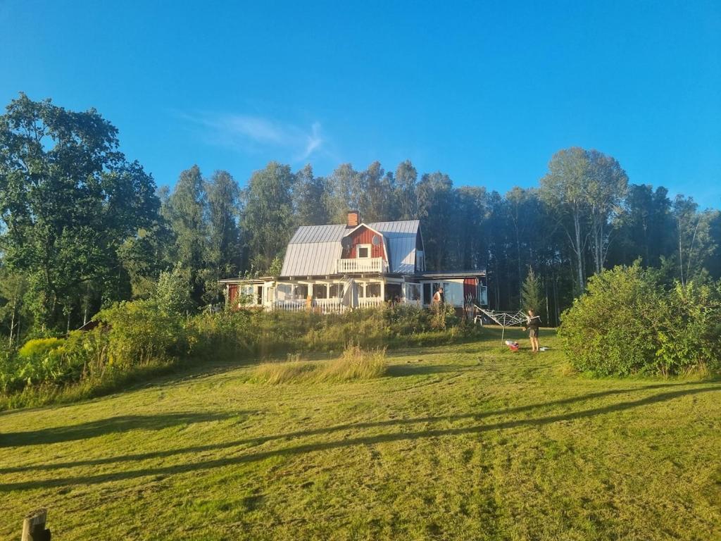una casa grande en la cima de un campo de hierba en Idyllic Lake House in Sweden, en Klässbol
