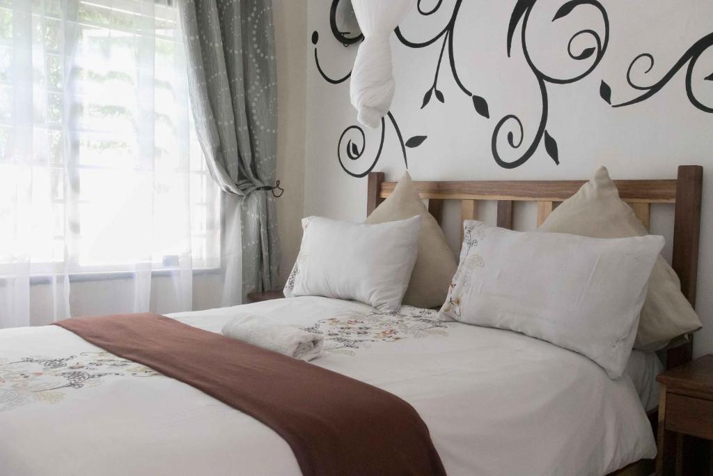 a bedroom with a bed with white sheets and pillows at Bwinji Mfumu Lodge in Chongwe