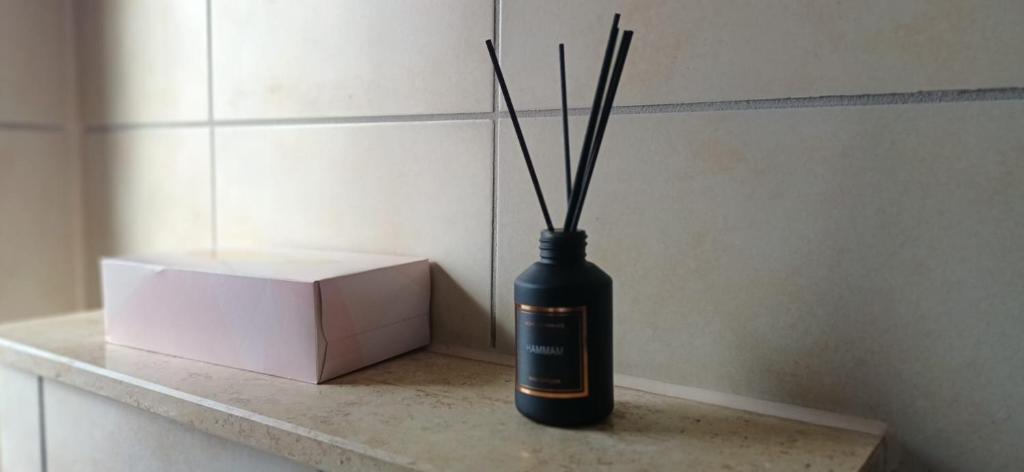 a black vase with sticks in it next to a box at M-Suites Petit - Near Frankfurt Airport in Hattersheim