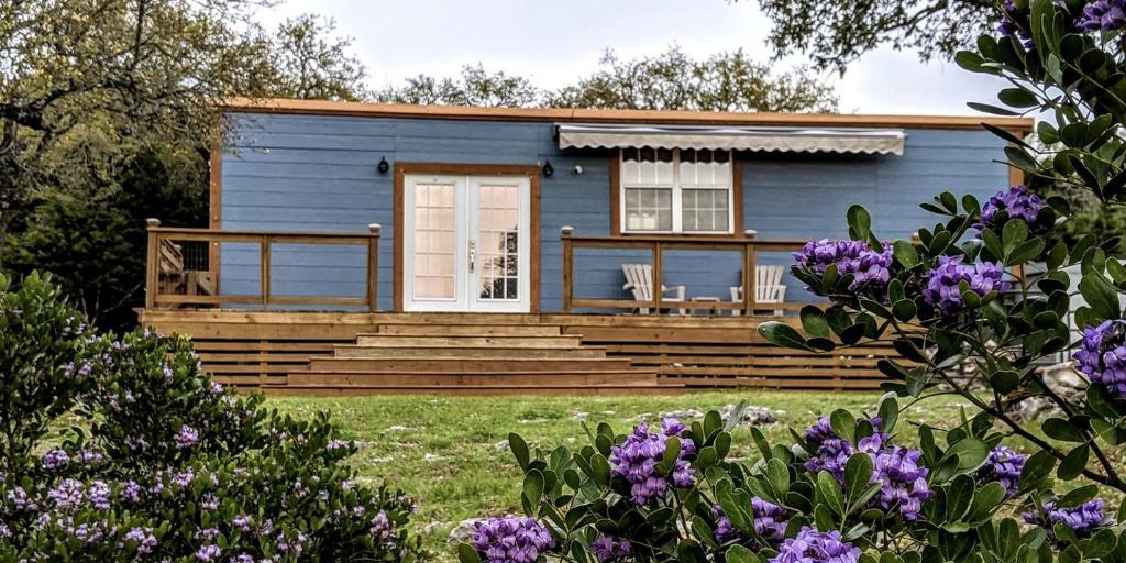 a blue house with two chairs in front of it at Tiny House with Amazing Views and Private Hiking Trails in Hill Country, Texas in Freedom Springs Ranch Airport