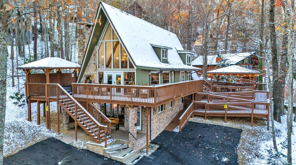 ein Haus mit einer umlaufenden Terrasse im Wald in der Unterkunft High Bear Activity, Handicap Ramp, Hot Tub, Fire Table, Game Room, Family Cabin in Gatlinburg