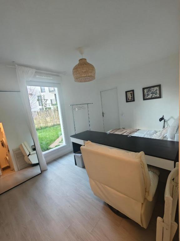 a bedroom with a bed and a couch and a window at Studio lumineux jardin privatif Paris & Disney in Noisy-le-Grand