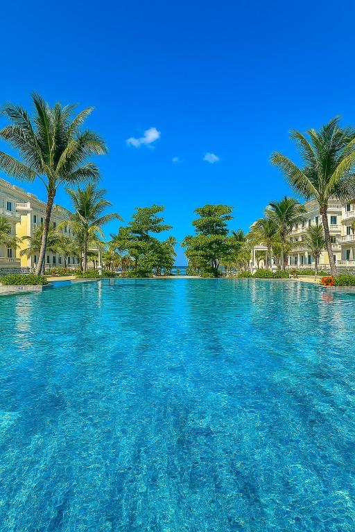 a large swimming pool with palm trees in the background at Kakashi Hotel Phú Quốc in Phú Quốc