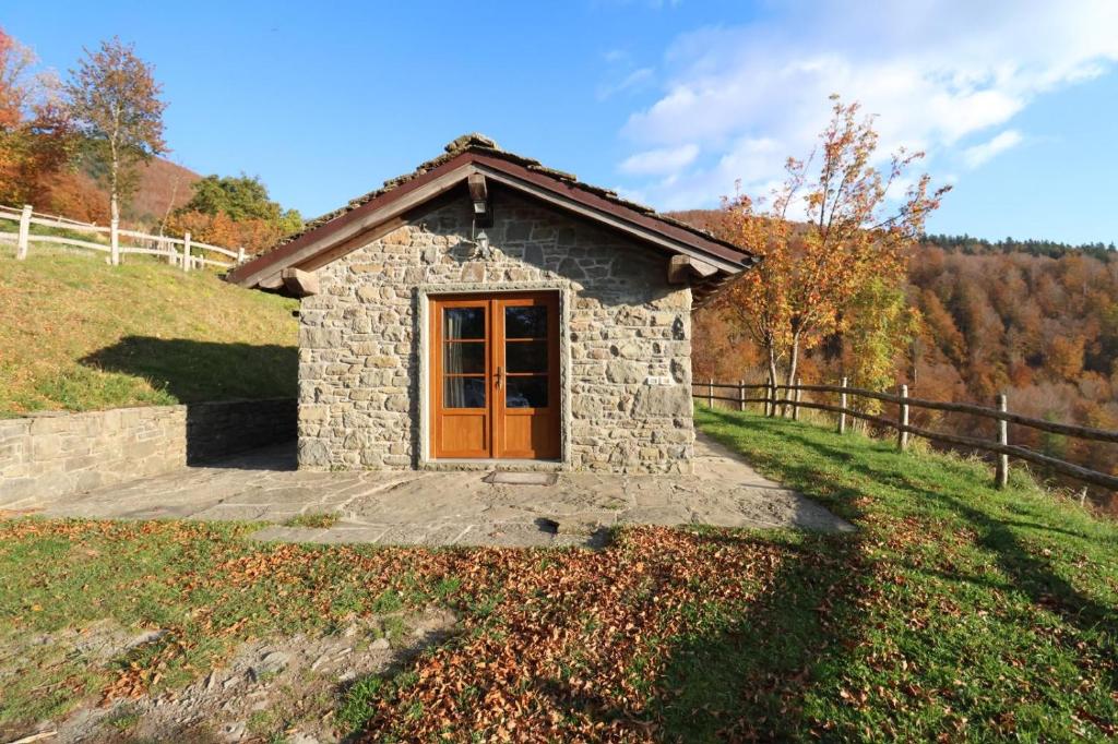 a small stone building with a wooden door on a hill at Agriturismo Le Roncacce in Abetone