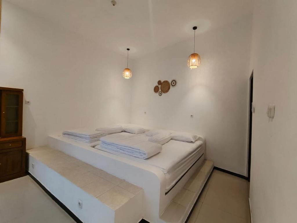 a white bed in a white room with two lights at savilla1 4 kamar dobel bed kolam renang dan biliard in Tlekung