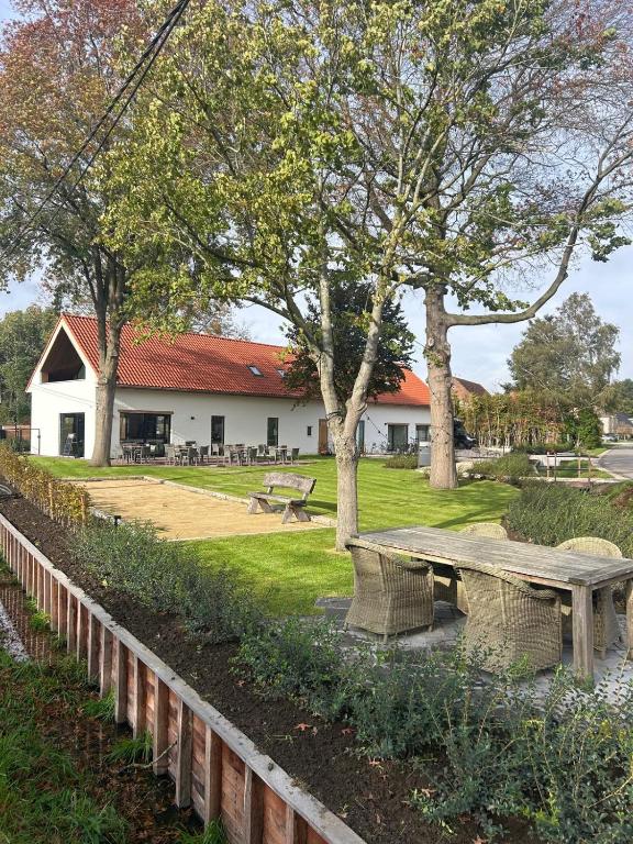 a park with a bench and trees and a building at De Kempische Hoef in Westerlo