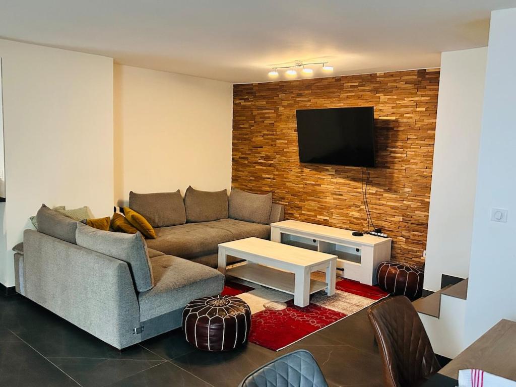 een woonkamer met een bank en een tv aan een bakstenen muur bij Au Bord du Logelbach in Colmar