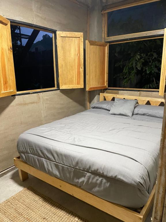 una cama en una habitación con dos ventanas en EB5 Escape Tzununa, Lake Atitlan Room #3 - two minute walk to the Lake, en Tzununá