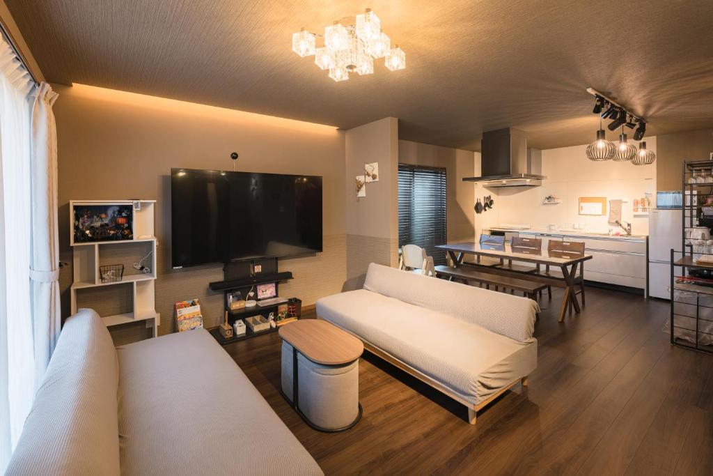 a living room with a couch and a tv at Noctis豊田 ジャグジー肩湯付お風呂75型TV 最大12名宿泊可能 in Toyota