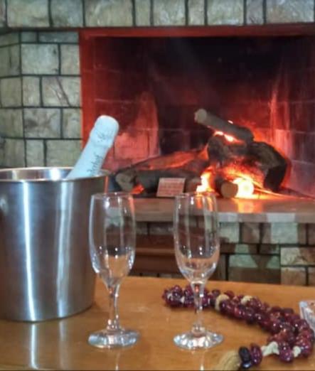 two wine glasses on a table in front of a fireplace at Giannad suite in Distomo