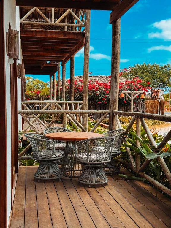 una mesa y sillas en una terraza de madera con flores en Morros da Barra chalé 05, en Barra Grande