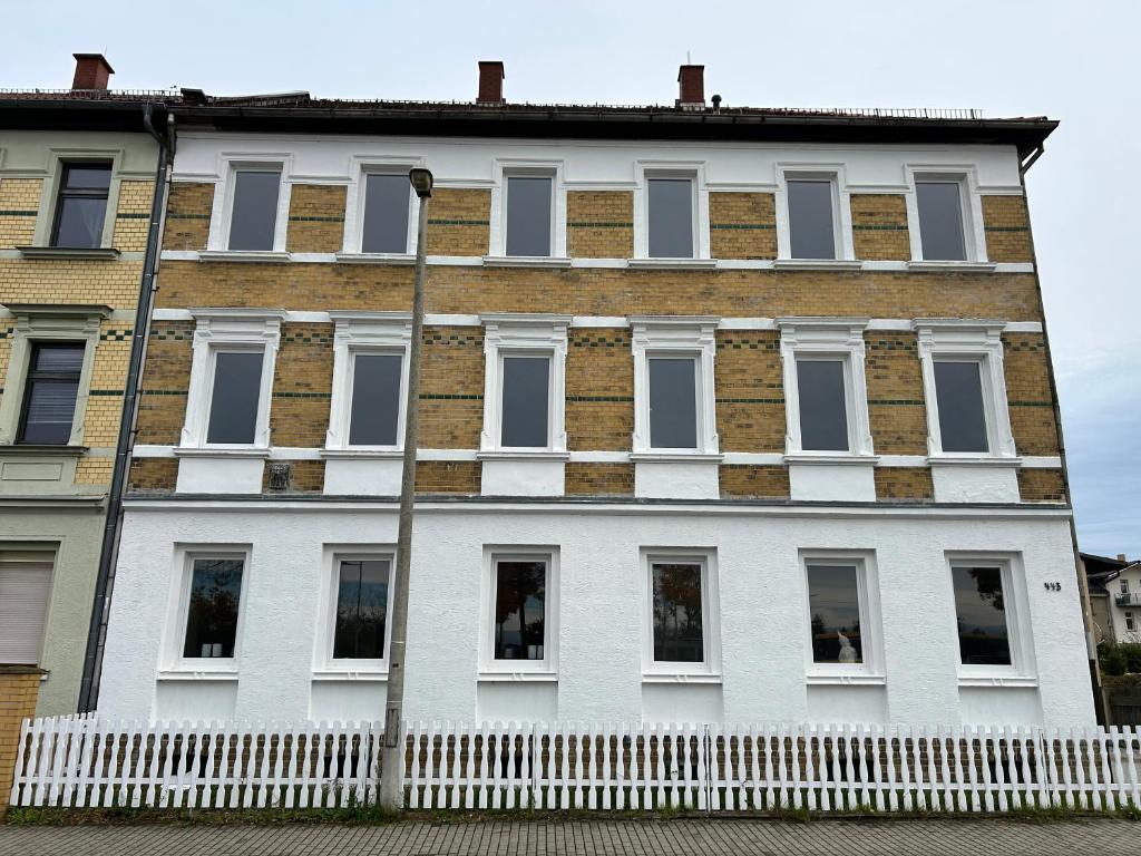 a white building with a white fence in front of it at GeBa Bed & Single Rooms in Leipzig
