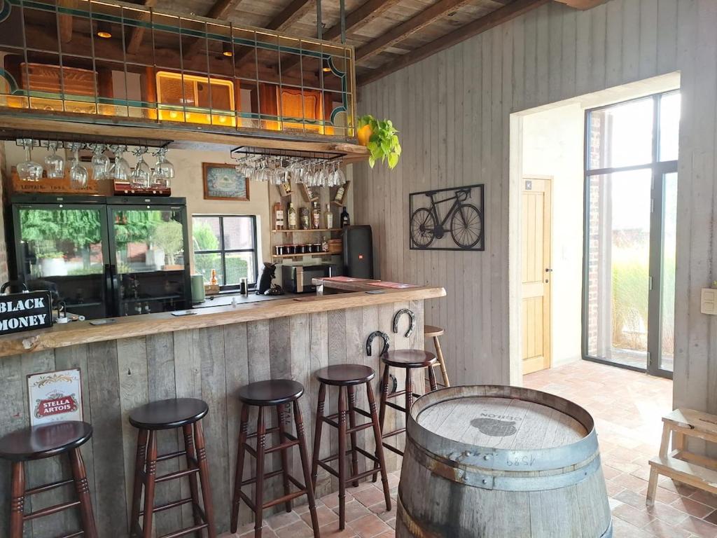 a bar with stools in a room with a counter at Vakantiehuis 6 personen-rustig en karaktervol in Geraardsbergen