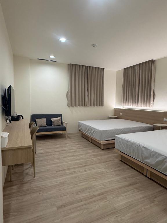 a hotel room with two beds and a couch at Jian Guo Hotel in Pingtung City