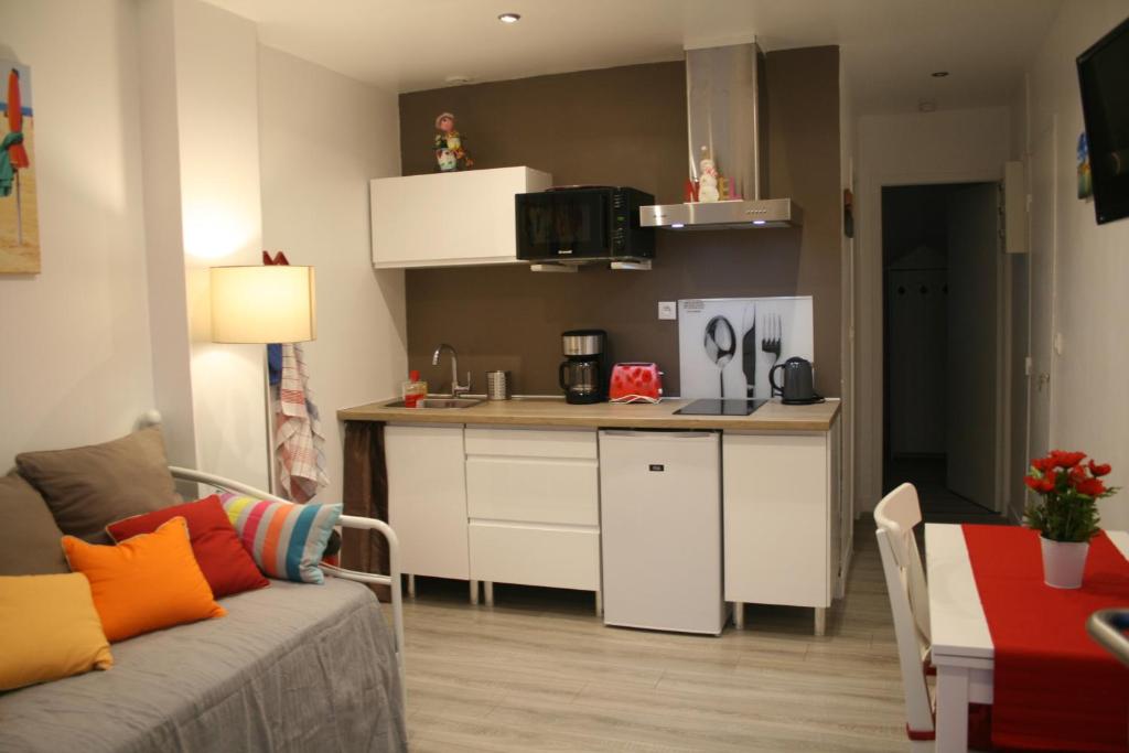een woonkamer met een bank en een kleine keuken bij Gîte Côte Fleurie Lisieux Centre in Lisieux