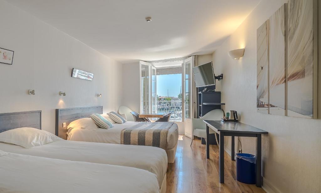 Cette chambre comprend deux lits et un bureau. dans l&#39;établissement Hotel La Marine, Vieux Port, à La Rochelle