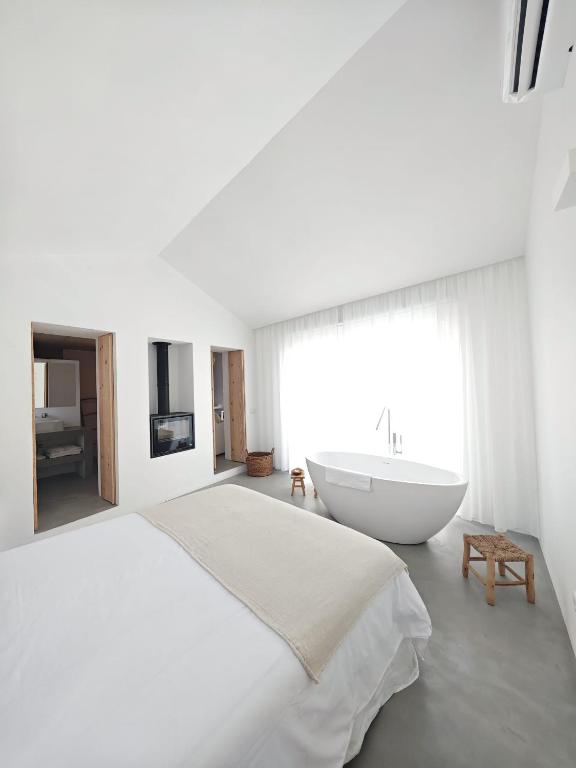 a white bedroom with a large bed and a bath tub at Casa d'Aldeia in Sonega