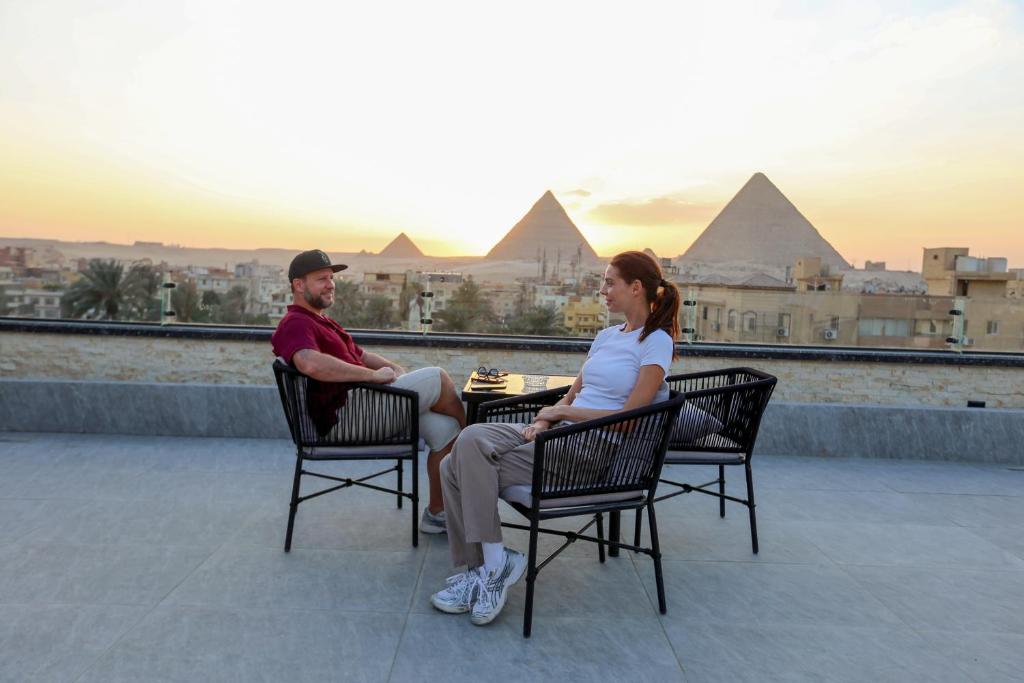 a man and woman sitting at a table with the pyramids at The Sacred Angle pyramids View in Cairo