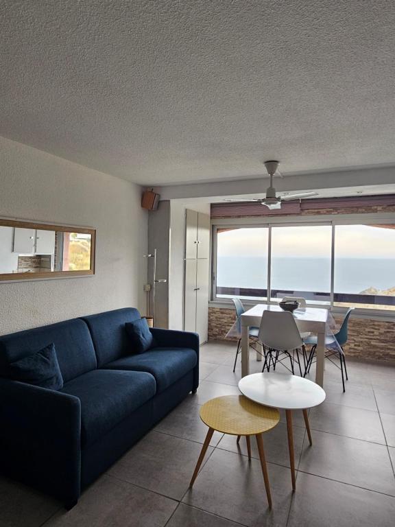 a living room with a blue couch and a table at Portvendres Sea view in Port-Vendres