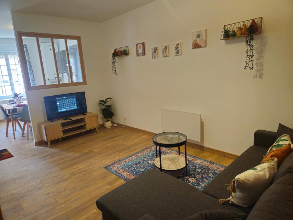 un salon avec un canapé et une télévision dans l'établissement Charmant appartement, spacieux et tout confort, à Charleville-Mézières
