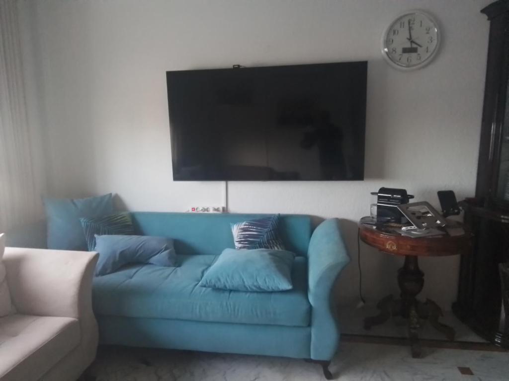 突尼斯Jasmin appart的客厅里设有一张蓝色的沙发,配有时钟