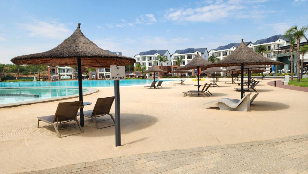 White House At The Blyde Crystal Lagoon في بريتوريا: مجموعة من الكراسي والمظلات بجانب حمام السباحة