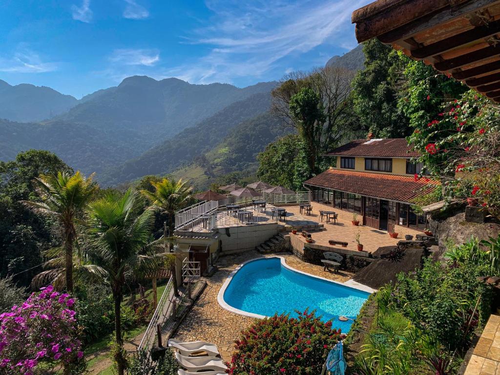 a house with a swimming pool and mountains in the background at Pousada Chale da Montanha in Petrópolis