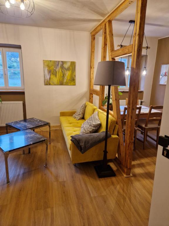 Una sala de estar con un sofá amarillo y una mesa. en Rebhaus Adams, en Moselkern