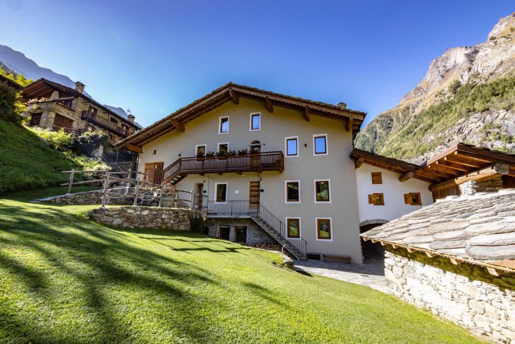 a large white house with a grassy yard at Lo Péyo - Le Four des Alpes in Rhemes-Saint-Georges