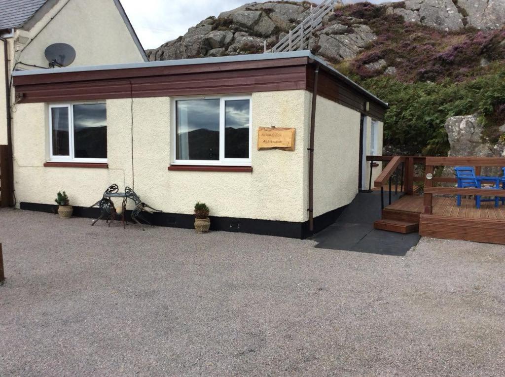 a small house with a porch and a mountain at The Captains Achmelvich in Lochinver