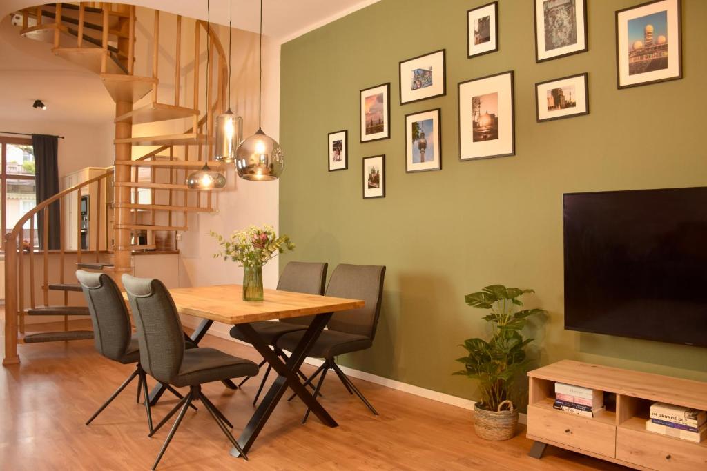 a dining room with a table and chairs and a television at Maisonette-Apartment für bis zu 6 Personen - Parkplatz - WLAN - Kingsize in Berlin