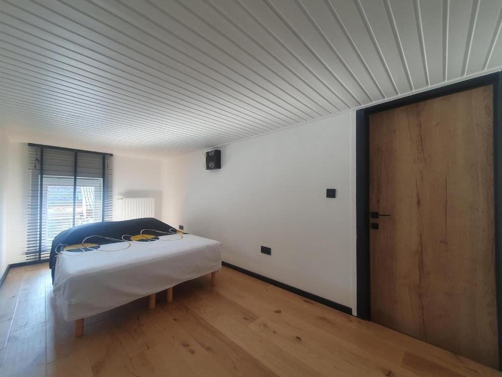 een slaapkamer met een bed en een houten vloer bij Le Mas d 'Ecaussinnes in Écaussinnes-dʼEnghien
