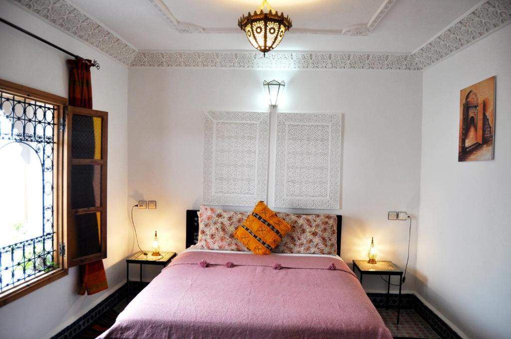 a bedroom with a pink bed and two lamps at Riad Tafoukt Fes in Fès