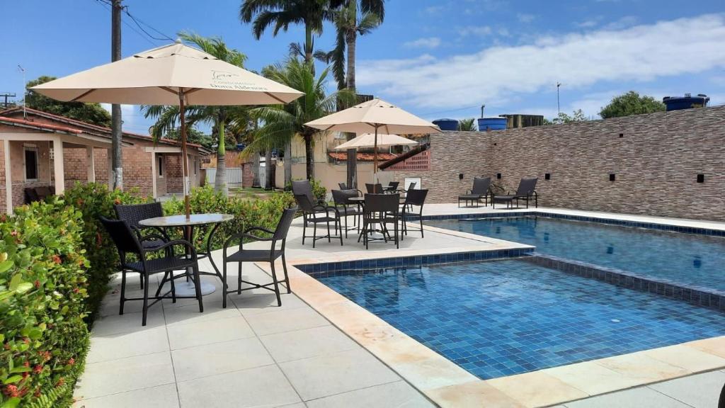 une piscine avec chaises, tables et parasols dans l'établissement Casa 85 m2 no FORTE 2 quartos campinho piscinas 2 vagas no estacionamento portaria ar condicionado para 8 pessoas, à Itamaracá