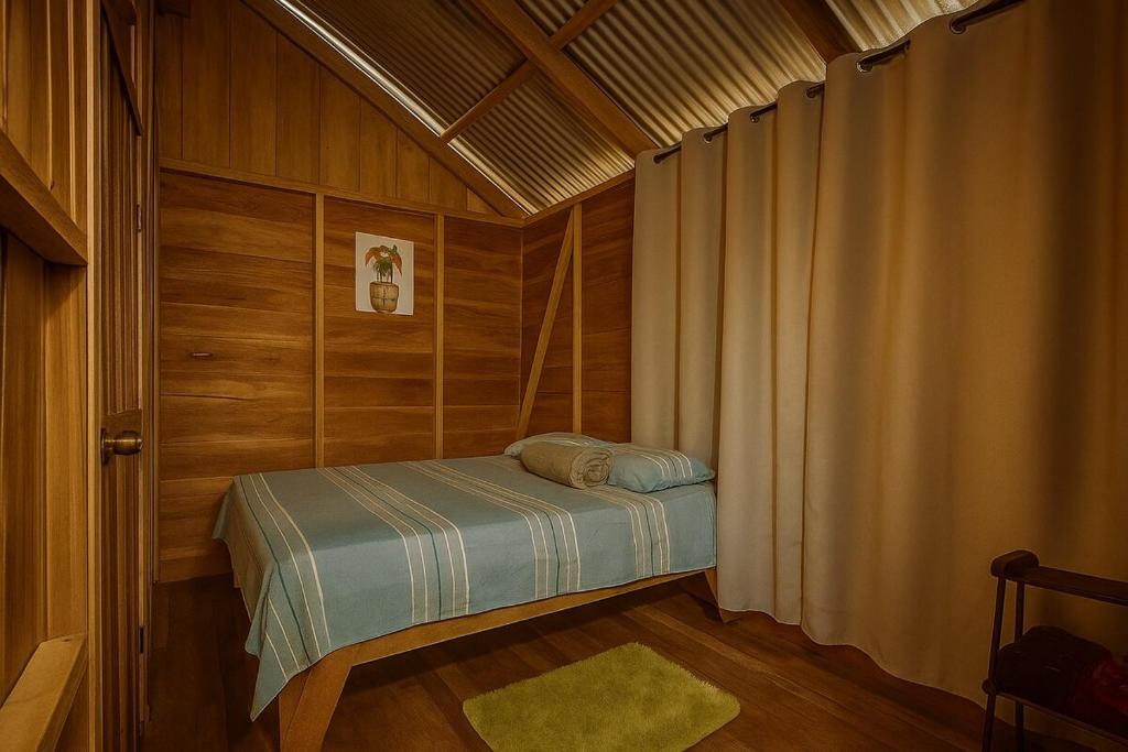 a small bedroom with a bed in a wooden room at Cabin -Treehouse La Tigra in San Gerardo