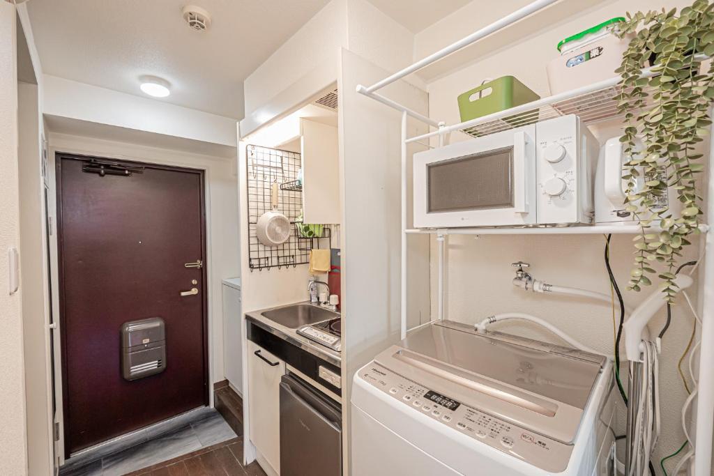 Una pequeña cocina con fregadero y microondas. en sakura 303, en Tokio