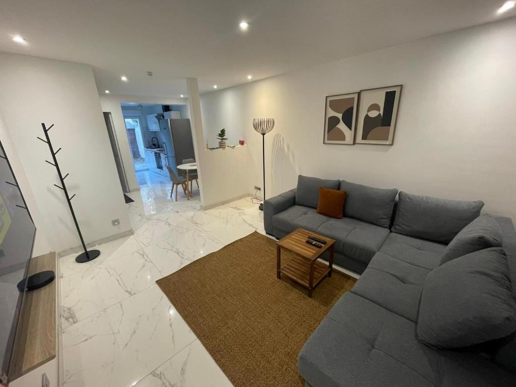 a living room with a gray couch and a table at Pavillion Peuple de l'Herbe in Carrières-sous-Poissy