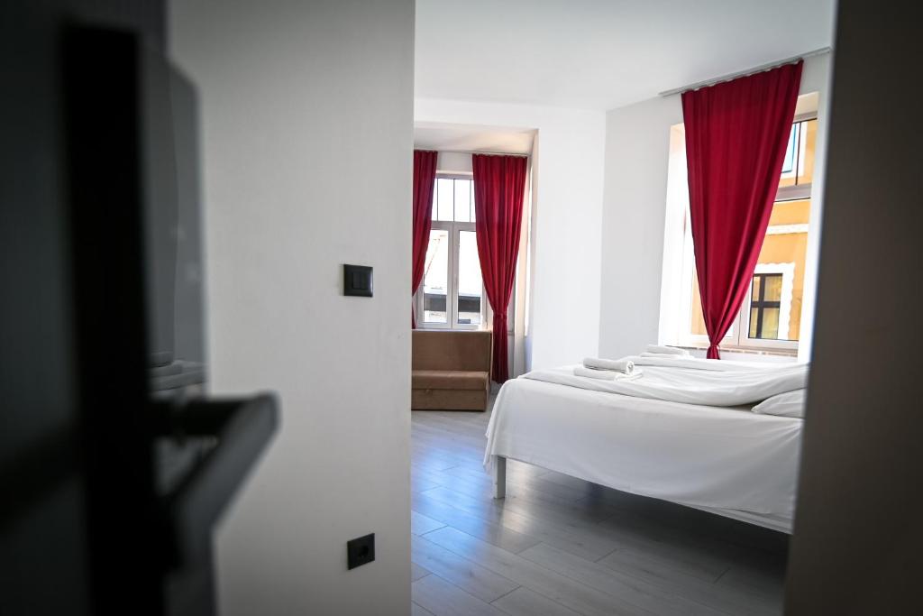 een slaapkamer met een bed en een raam met rode gordijnen bij Old Town Pearl Apartments in Sarajevo