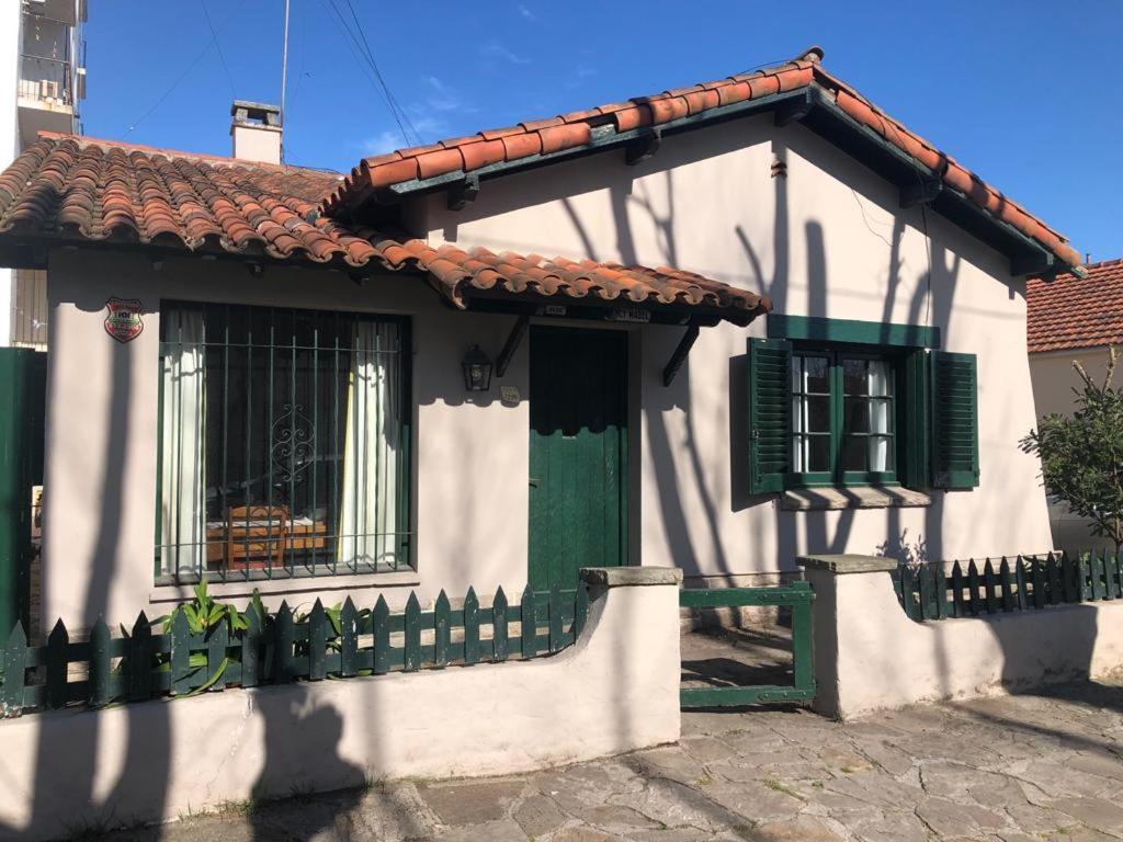 a white house with a green door and a fence at Alquilo Casa Miramar in Miramar