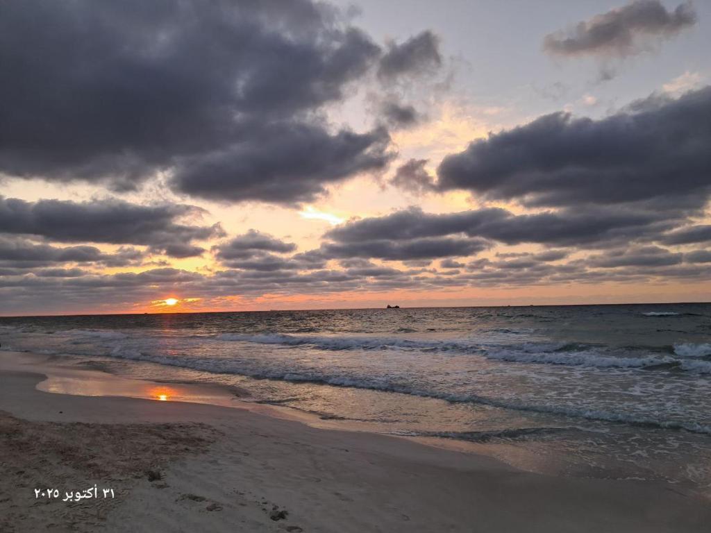 a sunset on a beach with the ocean at شقة بحر إسكندرية Bianchi Breeze in Alexandria