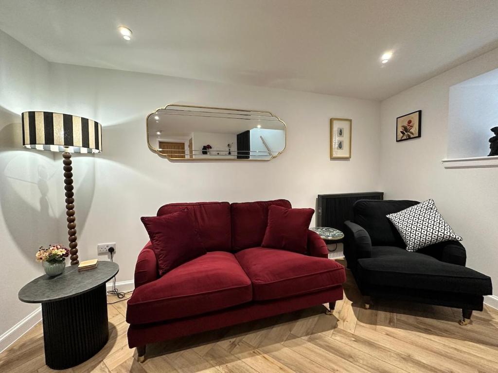 ein Wohnzimmer mit einem roten Sofa und einem Sessel in der Unterkunft Coorie-In Cottage in Whitehills