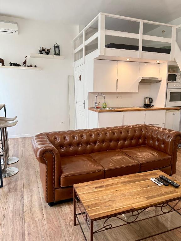un salon avec un canapé en cuir marron et une table dans l'établissement Appartement central, à Nice