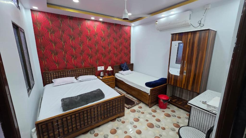 a bedroom with two beds and a red wall at Meera Hotel And Lodging in Badarpur