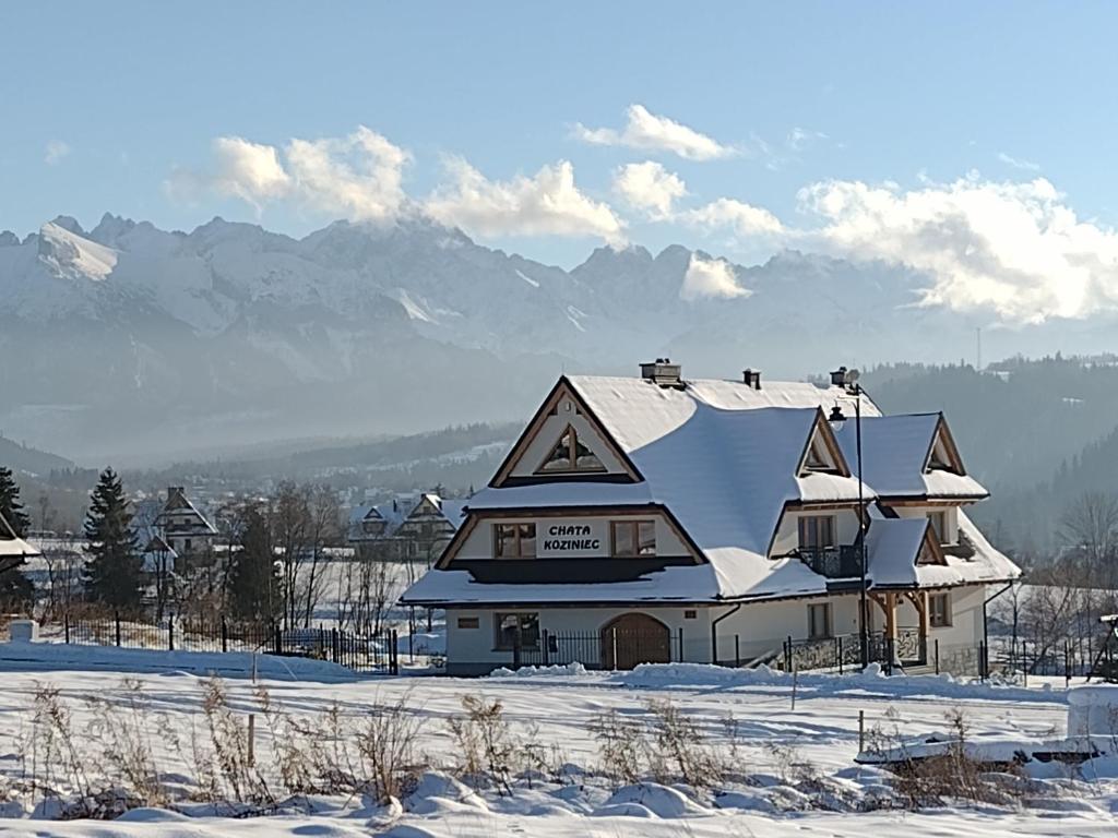 a house covered in snow with mountains in the background at Chata Koziniec przy wyciągu in Czarna Góra