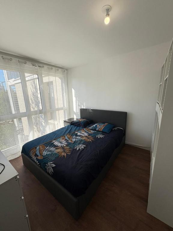 ein Schlafzimmer mit einem Bett in einem Zimmer mit Fenstern in der Unterkunft Chambre cozy avec lit double en étage in Bois-Colombes