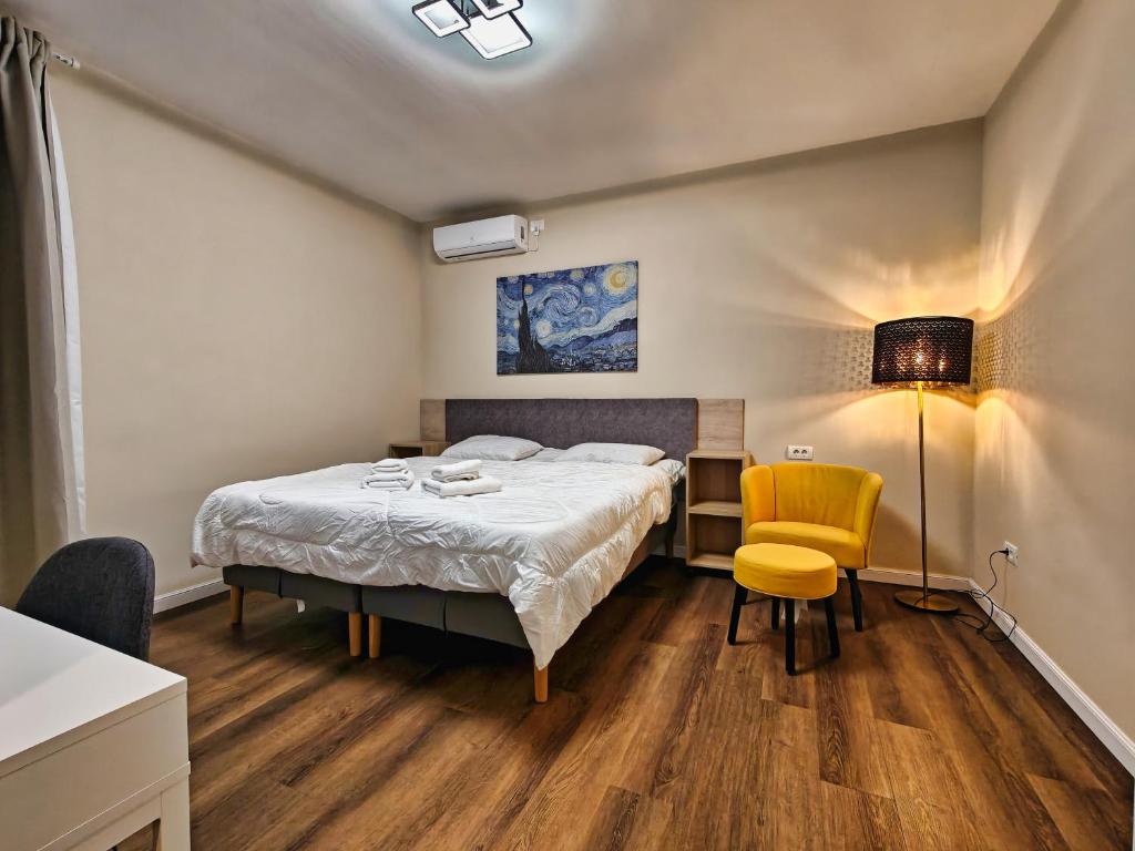 Piata Romana Suites & apartments - Pumo Properties في بوخارست: غرفة نوم بها سرير وكرسي أصفر