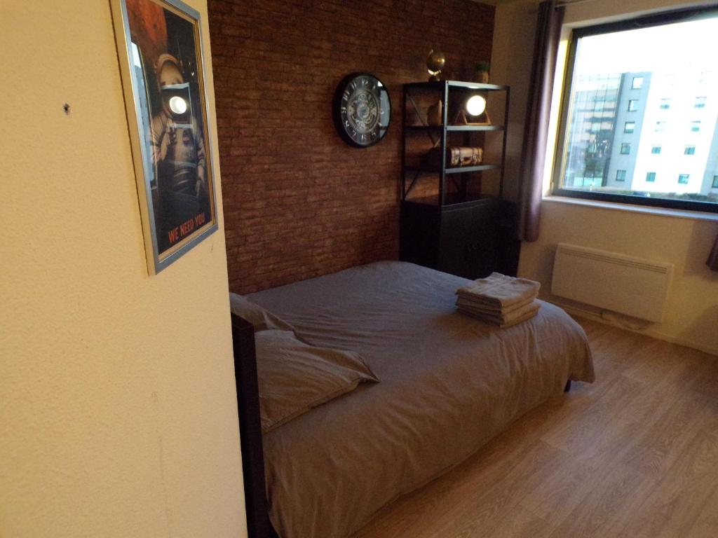 a bedroom with a bed and a clock on the wall at L'aventurier in Jaunay-Marigny