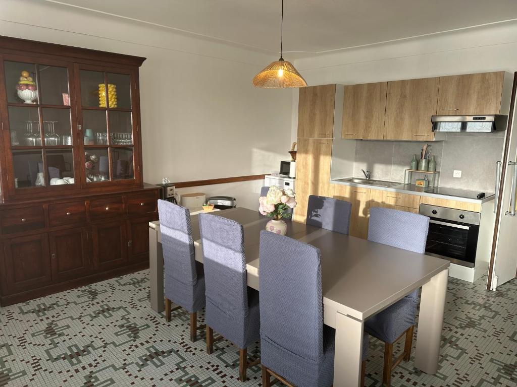 een keuken met een eettafel en blauwe stoelen bij Les mirabelliers 