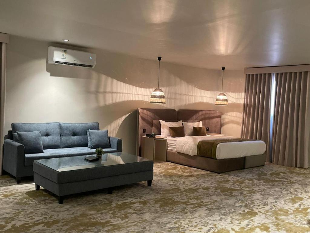 a bedroom with a bed and a couch and a table at شقق هذا منزلي فرع الربوة in Al Madinah