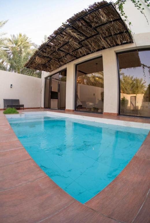 a swimming pool with blue water in front of a house at مجموعة سدرة فاطمة in Al Ahsa